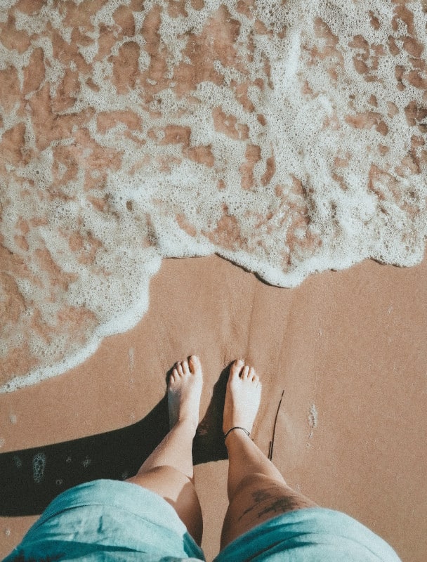 Des pieds sur la plage devant une vague