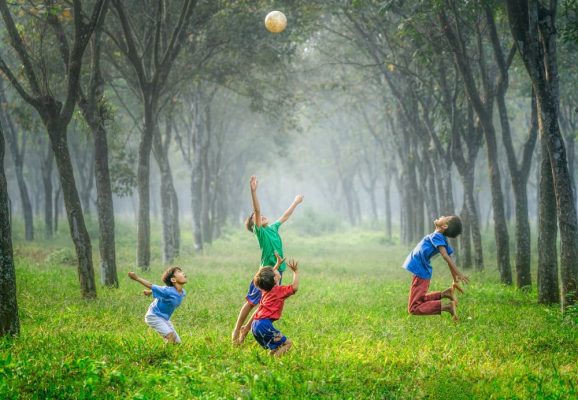 Des enfants jouant au ballon dans les bois